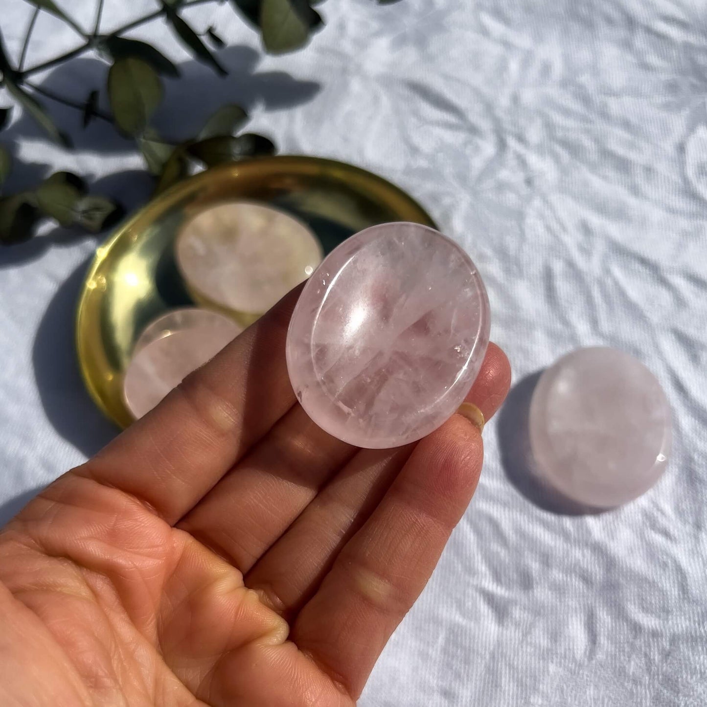Pale pink gemmy rose quartz crystal oval thumb stone balanced on an open hand
