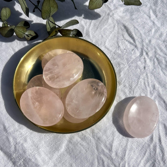 Pale pink gemmy rose quartz crystal oval worry stones in a shiny brass dish