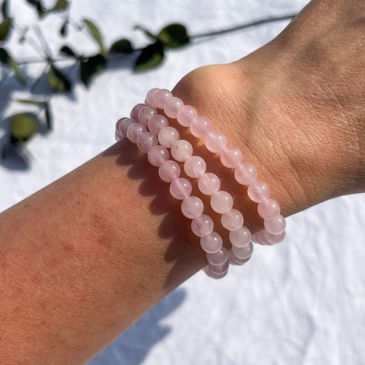 A lady's wrist sporting 3 pink coloured rose quartz crystal bead bracelets
