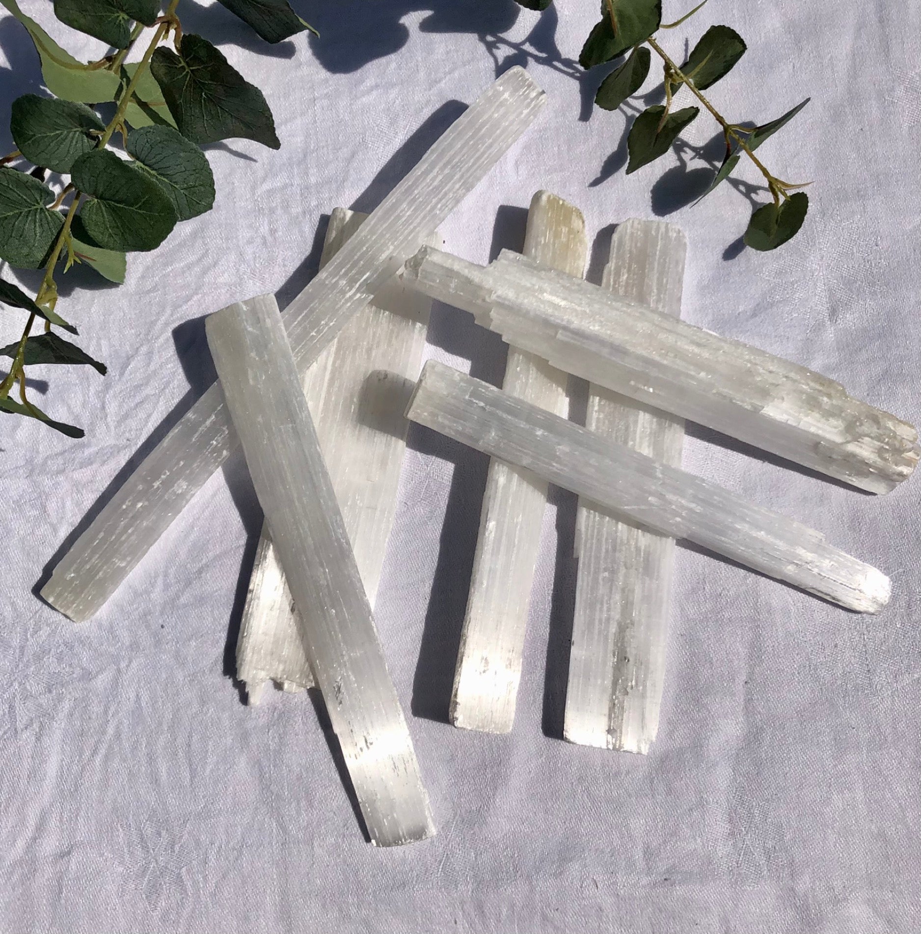 Several selenite rods stacked upon each other glistening in the sun