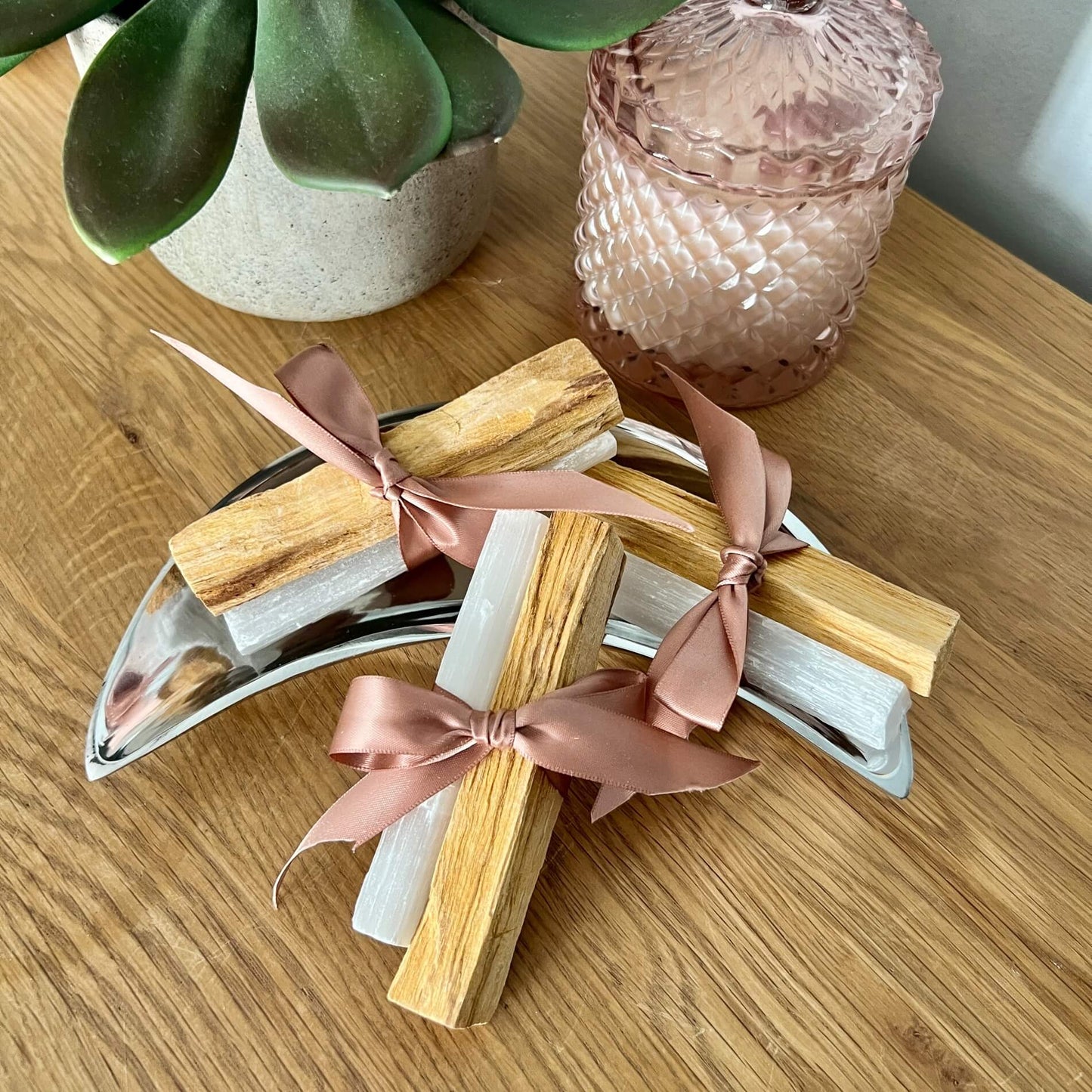 Palo Santo and Selenite sticks tied with pretty pink ribbon in a silver moon dish