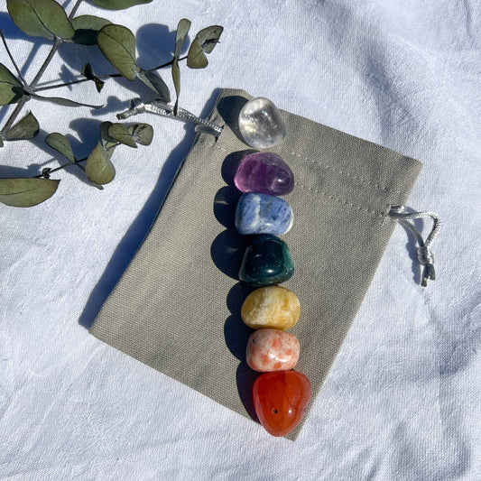 Seven crystals of each colour of the rainbow displayed on a grey cotton gift bag