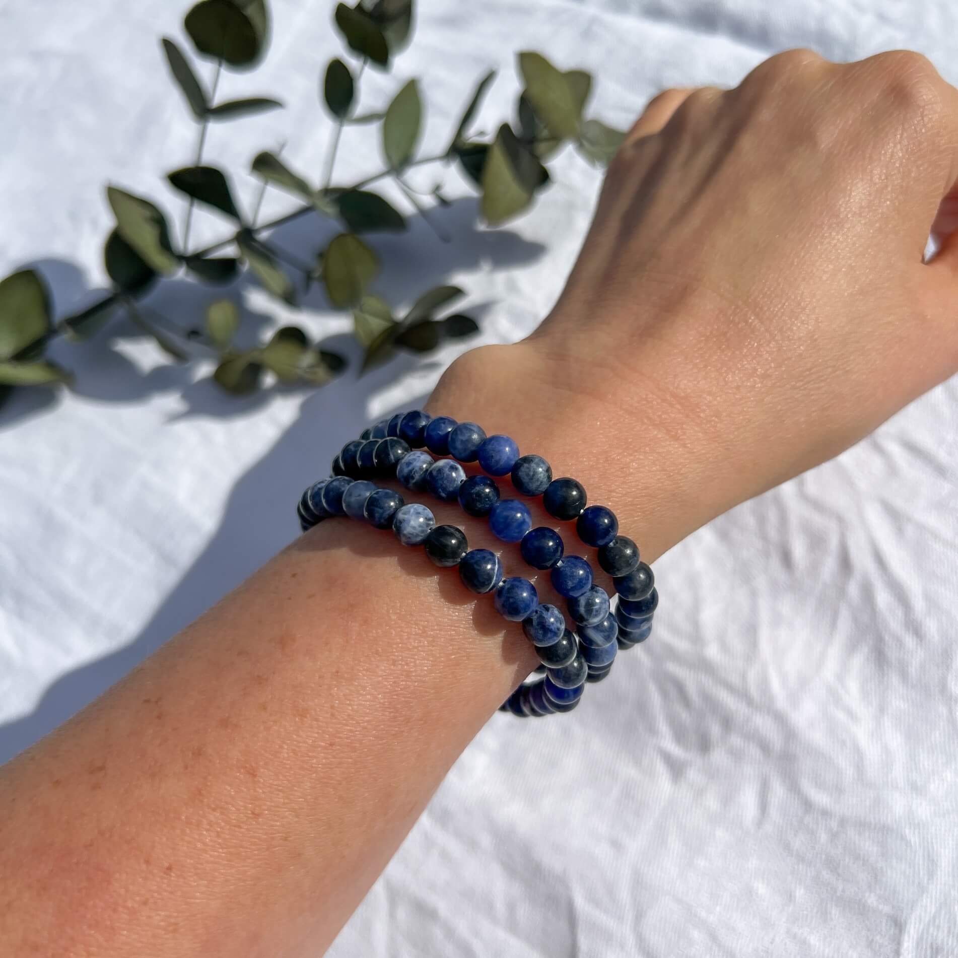 A ladies arm wearing Three blue and white patterned Sodalite crystal bead bracelets