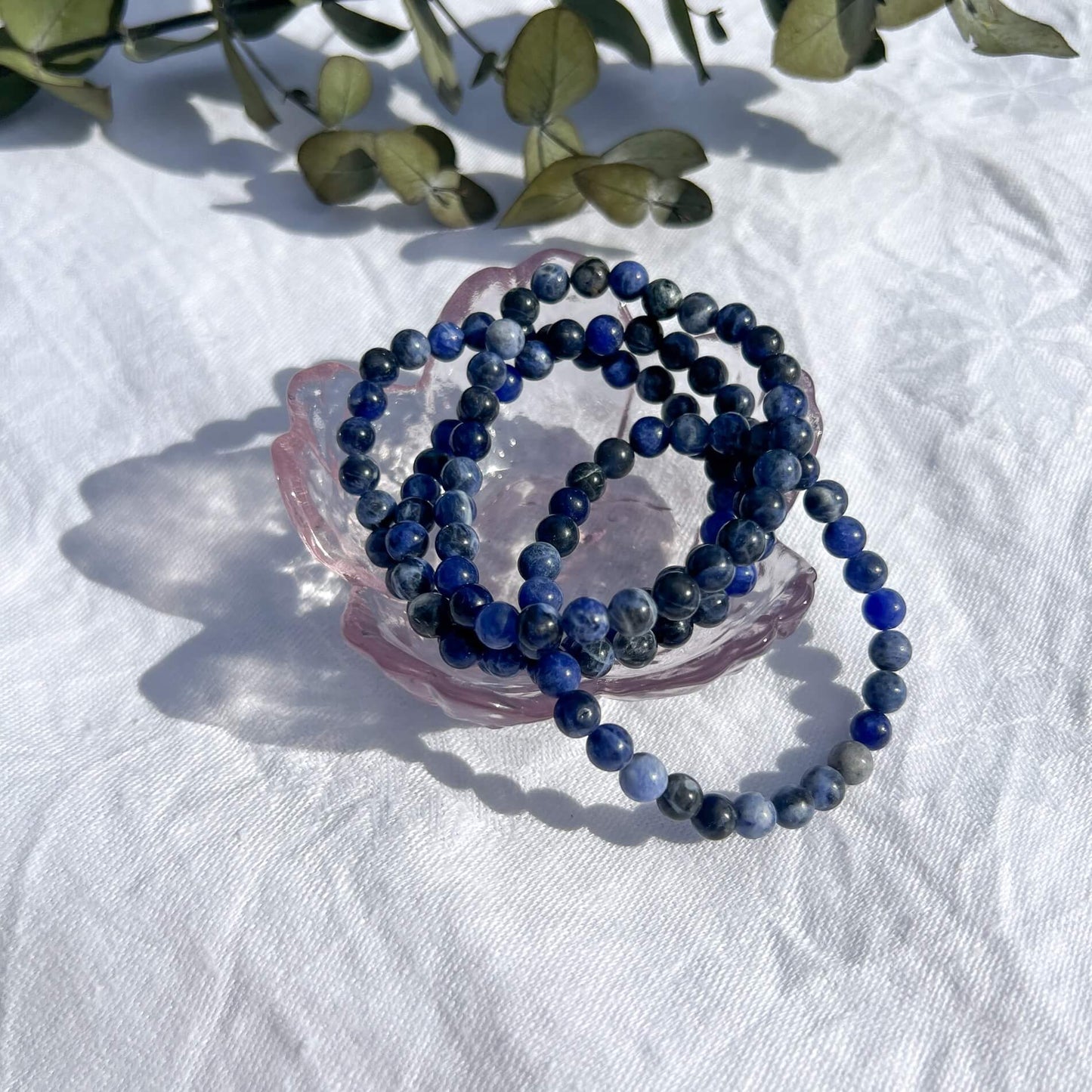 Glass trinket dish filled with blue and white Sodalite crystal bead bracelets