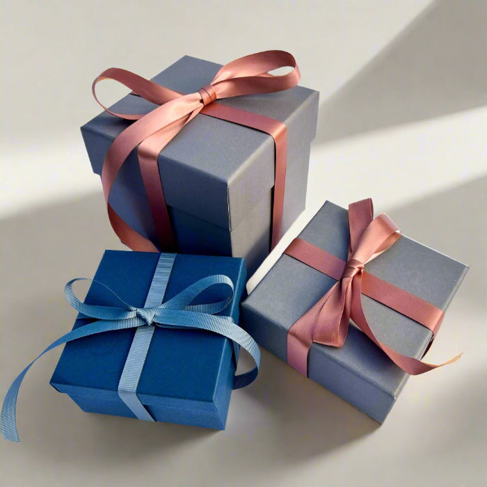 Three luxury grey and blue gift boxes tied with blue and pink ribbons